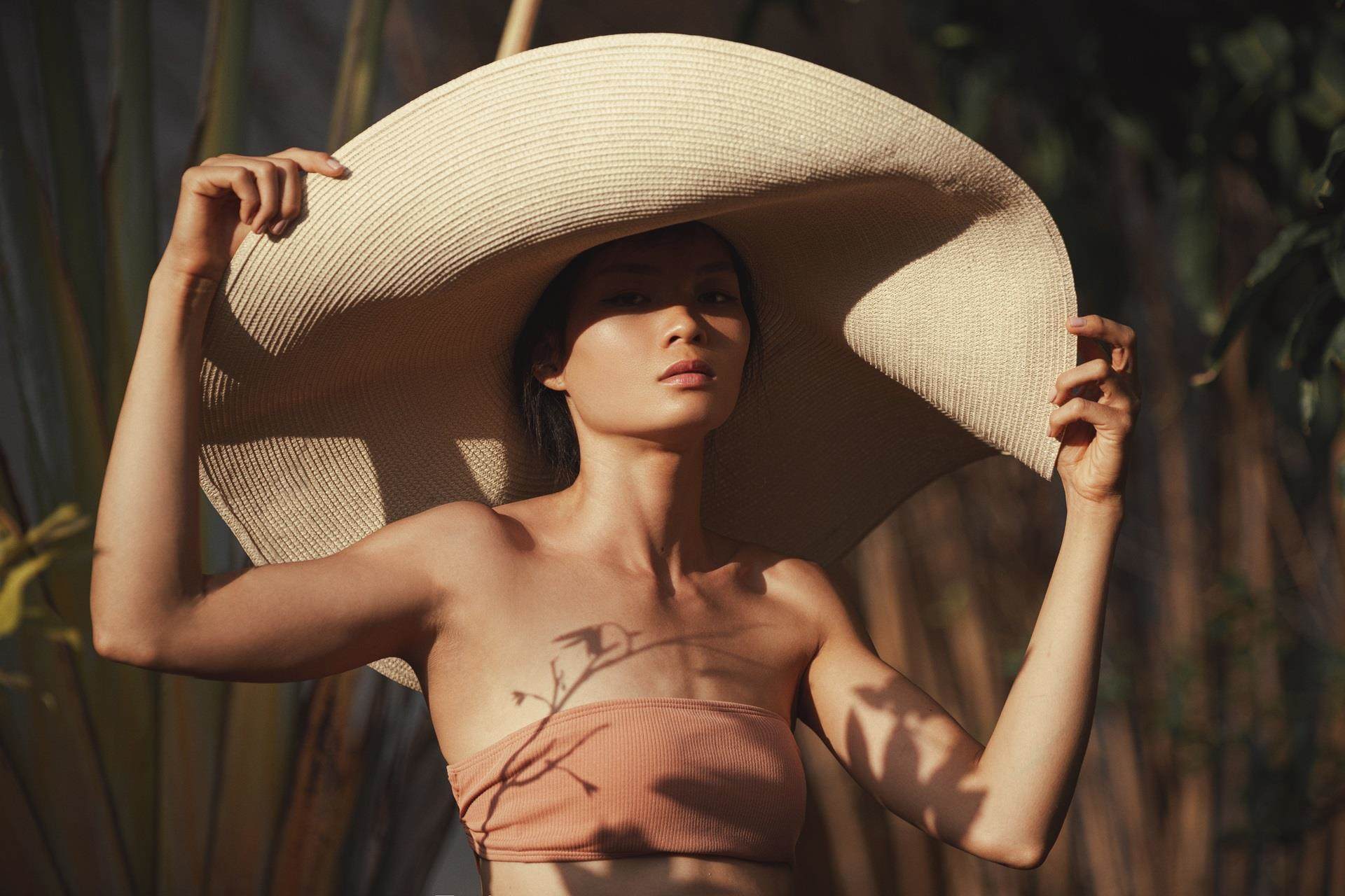 Women posing in extravagant cream hat in the sun