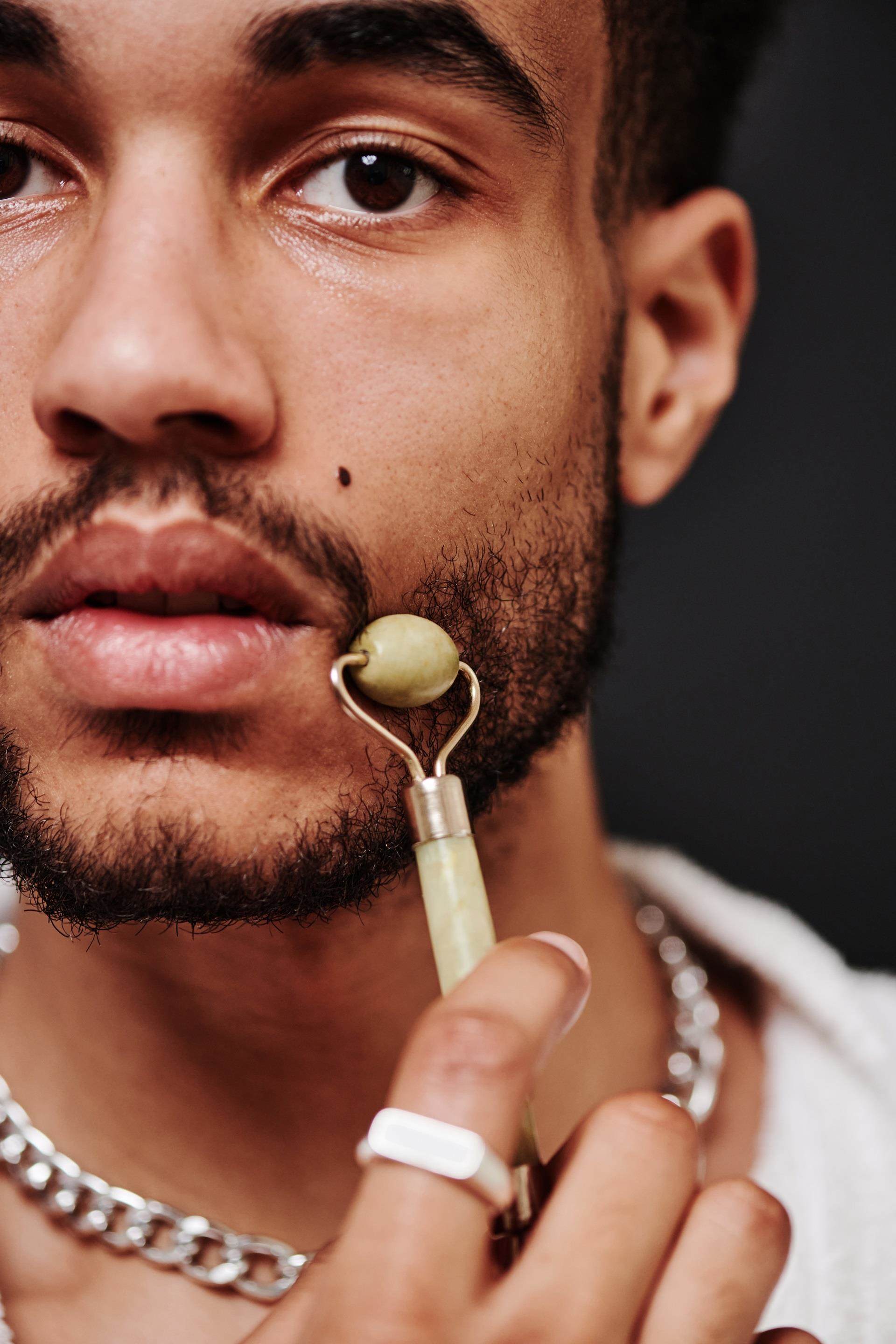 Male applying skin care to face using tool
