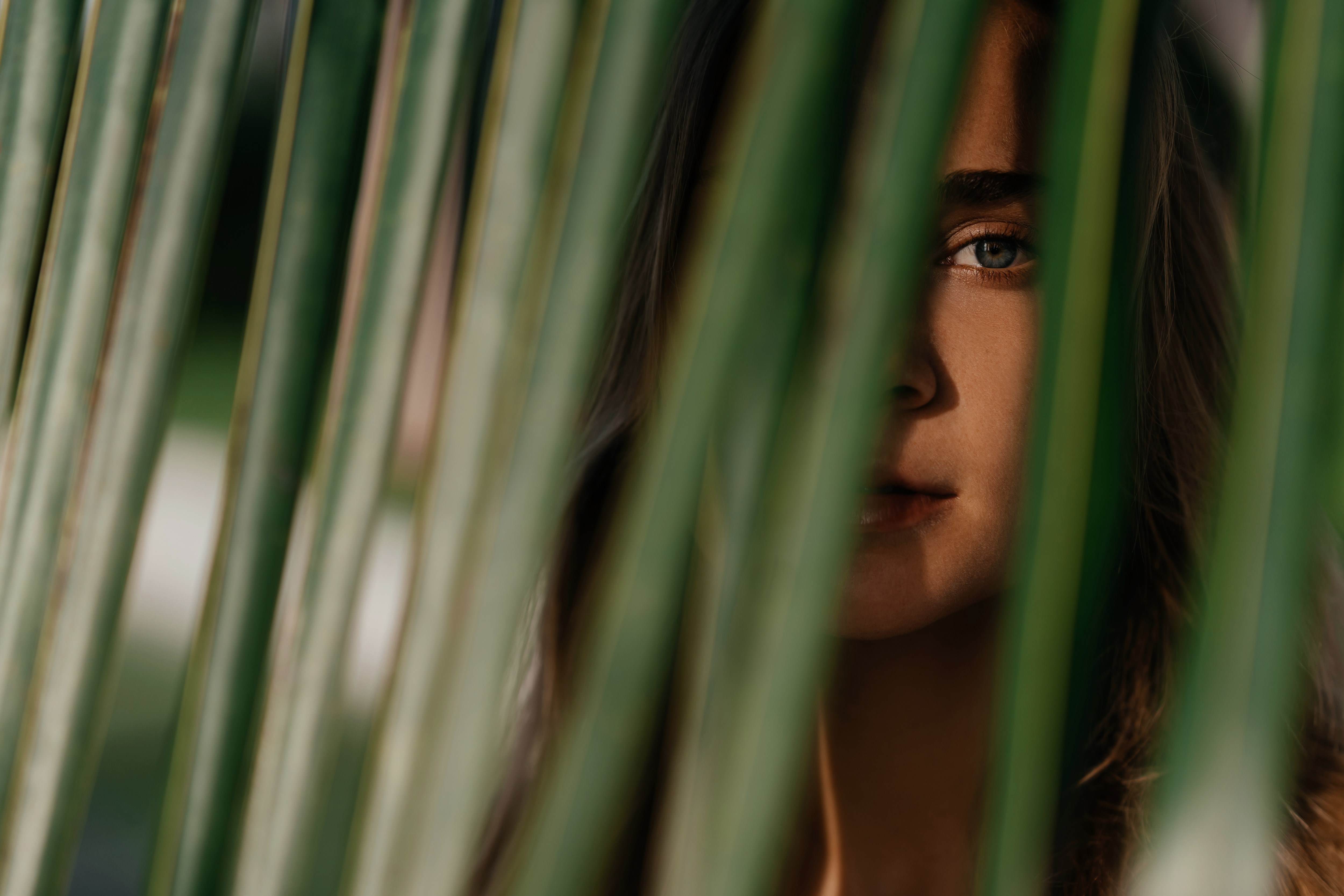 Women peaking though green plant with sun reflection